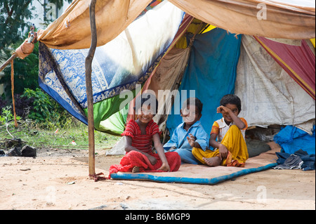 Felice povero indiano bambini seduti al di fuori della loro tenda home. Andhra Pradesh, India Foto Stock