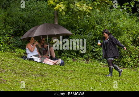 Giovane riparo dalla pioggia sotto ombrellone in terreni fangosi Vescovi Giardino Brecon al Jazz Festival 2008 Powys Wales UK Foto Stock