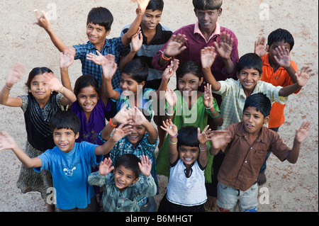 Indian i bambini giocando insieme rannicchiato in un gruppo sventolando la fotocamera in una zona rurale villaggio indiano. Andhra Pradesh, India Foto Stock