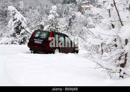 Auto SUV bloccato in un snow drift circondato da alberi coperti di neve fresca. Foto Stock