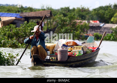 Donna locale pagaiando su una barca di legno caricate con cibo e varie cose in Chong Kneas villaggio galleggiante, Tonlè Sap lago, Cambogia Foto Stock