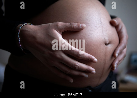 Una donna in stato di gravidanza nel suo terzo trimestre mantiene la sua gravidanza stomaco. Foto Stock