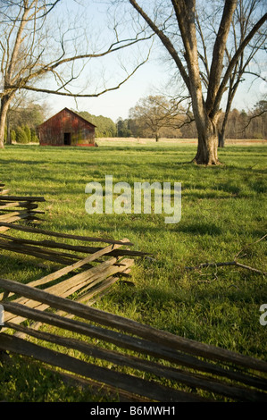 Granaio rosso verde nel campo erboso dietro Split Rail recinzione di legno Foto Stock