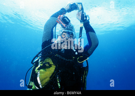 Scuba Diver affiorante e la bobinatura nel suo marcatore di superficie di boa. In subacquea alle Maldive. Foto Stock