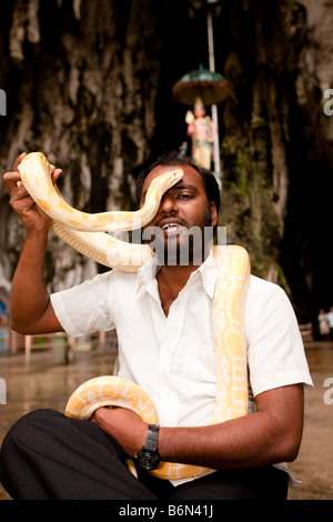 Uomo con albino python all'ingresso delle Grotte Batu Foto Stock