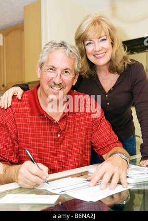 Bella coppia matura andando oltre le fatture insieme e sorridente Foto Stock