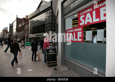 Gli amanti dello shopping a piedi passato chiudendo i segni di vendita nella vetrina di un negozio in una zona pedonale del Regno Unito centro città di Belfast Foto Stock