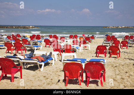 I turisti hanno un riposo sulla spiaggia mediterranea sul blu scuro sedie a sdraio Foto Stock