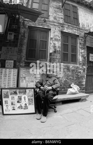 Una molto bella bella ed elegante signora cinese a 93 anni si siede di fronte a lei book store in Guangzhou con Mao propaganda. Foto Stock