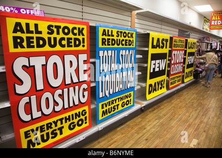 Prezzi di magazzino ridotte segni di liquidazione con gli scaffali vuoti in Woolworths shop chiusura REGNO UNITO Foto Stock