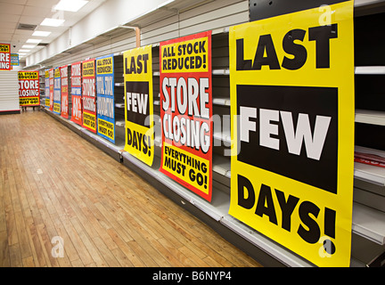 Prezzi di magazzino ridotte segni di liquidazione con gli scaffali vuoti in Woolworths shop chiusura REGNO UNITO Foto Stock