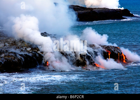 Immagine di lava fusa scorre giù per la collina e nel mare mentre il vapore sale tutto Foto Stock