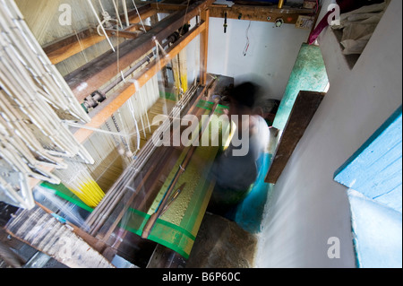 Indian uomo al lavoro di un telaio di tessitura a mano facendo un sari di seta in un Indiano cottage. Andhra Pradesh, India. Esposizione lunga Foto Stock