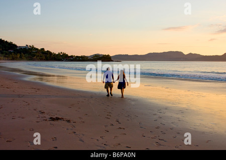 Giovane gode passeggiando lungo la spiaggia al tramonto lungo il Flamingo Beach in Costa Rica Foto Stock
