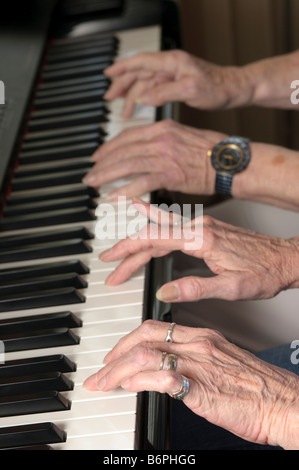 Stretta di mano di due anziane signore suonare pianoforte a quattro mani Foto Stock