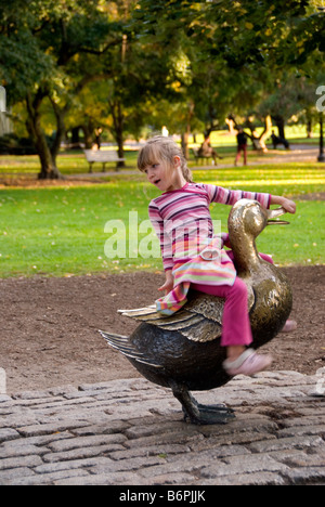 Ragazza Ragazzo seduto sulla sig.ra Mallard scultura 'Make modo per le ochette' in Boston Public Garden Foto Stock