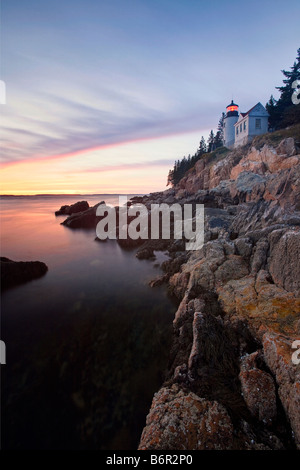 Vista verticale di un faro su una scogliera al tramonto porto basso Capo Faro Maine Foto Stock