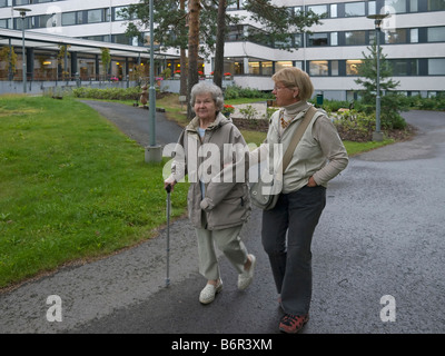Donna middleaged aiutando la madre avente una passeggiata in una strada Foto Stock