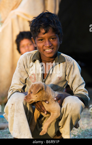 Poveri nomadi ragazzo indiano a giocare con un cucciolo di cane. Andhra Pradesh, India Foto Stock