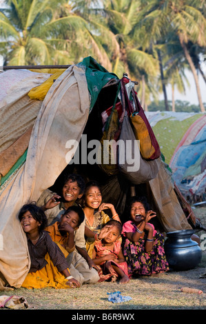 Povero indiano nomadi bambini seduti nella loro tenda a casa nella luce del mattino. Andhra Pradesh, India Foto Stock