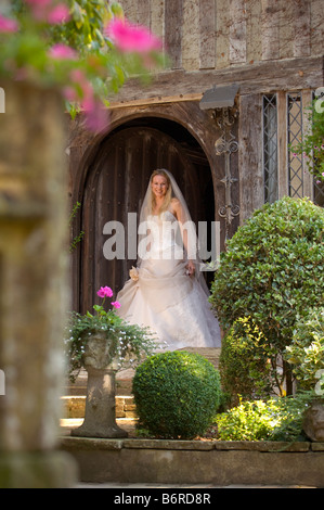 Un sorridente sposa esce dalla porta di casa di paese designer di indossare abiti da sposa da Becly Drinan. Foto da Jim Holden. Foto Stock