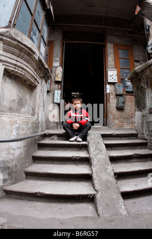 Asian bambino seduto nella parte anteriore del tubo flessibile dei familys nel vecchio quartiere di Guangzhoum Guangdong Cina Asia Foto Stock