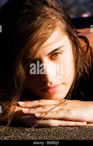 Green Eyed beauty recante sulla sabbia Foto Stock