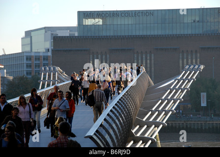 Vista di persone che attraversano il Millennium Bridge con Tate Modern dietro, London, Regno Unito Foto Stock