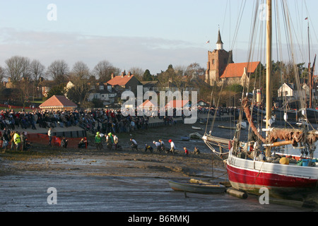 I concorrenti nell'annuale Mad Maldon gara di fango di raggiungere il traguardo. Fiume Blackwater, Essex, Regno Unito Foto Stock