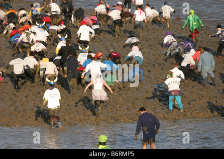 I concorrenti nell'annuale Mad Maldon gara di fango. Fiume Blackwater, Essex, Regno Unito Foto Stock