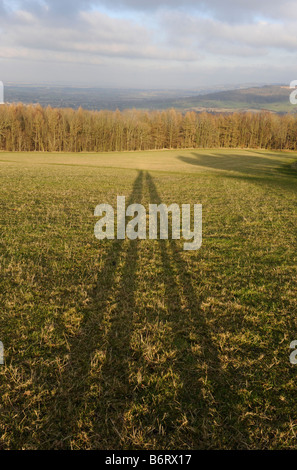 Le ombre di una coppia di escursionisti che si estendono su di una collina sulla Cotswold modo sentiero Foto Stock