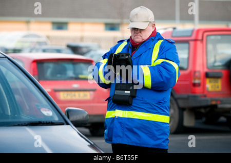 Un parcheggio auto privato attendant indossando giacca blu tenendo i dettagli di un'auto parcheggiata nel suo notebook elettronico, REGNO UNITO Foto Stock