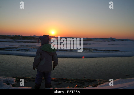 Bambino guardando tramonto in inverno Foto Stock