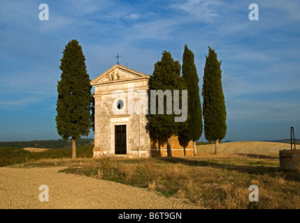 Un piccolo telecomando cappella circondata da cipressi in Toscana, Italia. Grande sky e colori del paesaggio Foto Stock