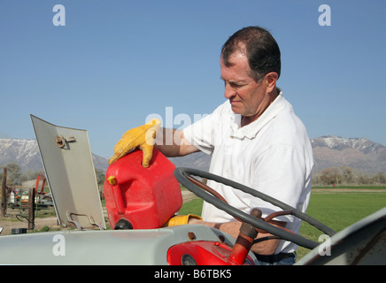 Senior uomo invecchiato il riempimento di un trattore serbatoio per gas con gas dal gas può Foto Stock