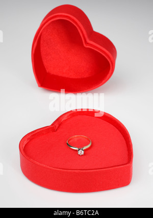 A forma di cuore il giorno di san valentino scatola con coperchio e anello diamante interno su sfondo bianco Foto Stock