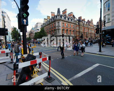 Le persone che attraversano la strada con rotte semaforo su una trafficata Oxford Street London REGNO UNITO Foto Stock