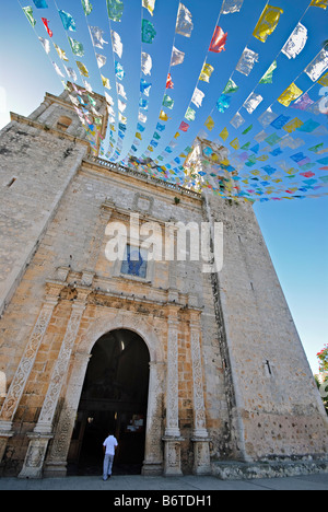Iglesia De San Servacio facciata della chiesa Valladolid Messico | VALLADOLID, Messico - stringhe di papel picado, striscioni messicani di carta tagliata, si aprono sopra un visitatore entrando nel portale in pietra scolpita dell'Iglesia de San Servacio. La porta ornata della facciata e la borchia risalgono alla ricostruzione della chiesa del 1706, intrapresa dopo che la struttura originale del 1545 fu demolita a seguito di un omicidio dichiarato profanazione dello spazio sacro. Foto Stock