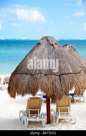 Sedie a sdraio e ombrelloni Playa Mujeres Mexico // PLAYA MUJERES, Messico - sedie a sdraio e ombrelloni di paglia sono disposti sulla spiaggia di sabbia bianca di Playa Mujeres al sole. Questa destinazione turistica si trova sulla costa nord-orientale della penisola dello Yucatan, a circa 10 chilometri (6 miglia) a nord di Cancun. Playa Mujeres è conosciuta per le sue spiagge incontaminate e gli edifici di lusso che hanno trasformato questa zona costiera in una popolare destinazione turistica. La spiaggia fa parte della più ampia regione della Riviera Maya, che si estende lungo la costa caraibica del Messico. La zona si trova Foto Stock