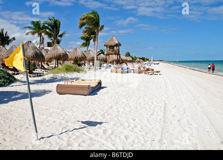 Playa Mujeres Beach Resort Cancun Mexico // PLAYA MUJERES, Messico - sedie a sdraio e ombrelloni di paglia sono disposti sulla spiaggia di sabbia bianca di Playa Mujeres al sole. Questa destinazione turistica si trova sulla costa nord-orientale della penisola dello Yucatan, a circa 10 chilometri (6 miglia) a nord di Cancun. Playa Mujeres è conosciuta per le sue spiagge incontaminate e gli edifici di lusso che hanno trasformato questa zona costiera in una popolare destinazione turistica. La spiaggia fa parte della più ampia regione della Riviera Maya, che si estende lungo la costa caraibica del Messico. L'area si trova all'interno Foto Stock