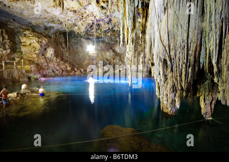 VALLADOLID, Messico: Le acque cristalline del Cenote Xkeken illuminano un blu etereo sotto una cupola rocciosa. Le stalattiti pendono dal soffitto di questa caverna sotterranea, mentre un raggio di luce del sole illumina la tranquilla piscina, creando un'atmosfera mistica in questa meraviglia naturale vicino a Valladolid, Yucatán. Foto Stock