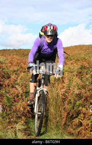 Maschio adulto mountain biker la discesa attraverso bracken su off-road ride in North York Moors Foto Stock