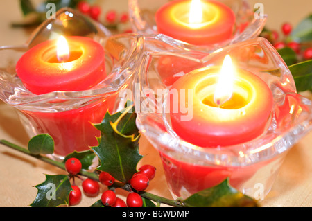 Rosso di piccole candele votive con agrifoglio e bacche rosse come un centrotavola di natale. Foto Stock