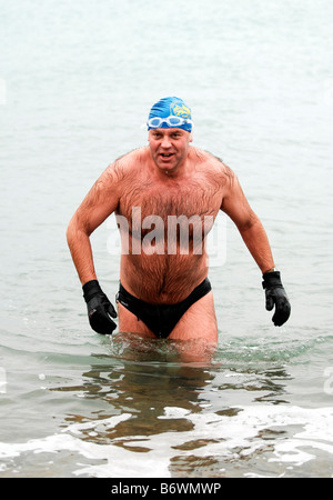 Un membro di Brighton Scuola Nuoto emerge dal freddo canale inglese dopo aver completato un giorno di nuovi anni nuotare Foto Stock