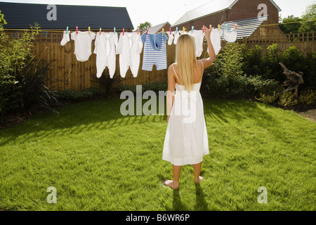 Donna con bambino vestiti sulla linea di abbigliamento Foto Stock
