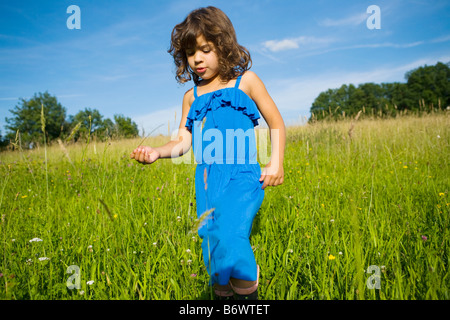 Una ragazza camminare attraverso un campo di erba lunga Foto Stock