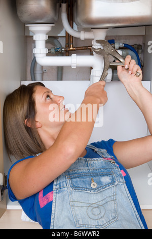 Una giovane donna di riparazione di un lavandino Foto Stock