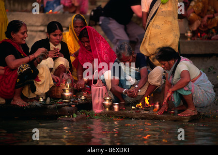 India, Varanasi, fiume Gange, donne che offrono offerte all'alba Foto Stock