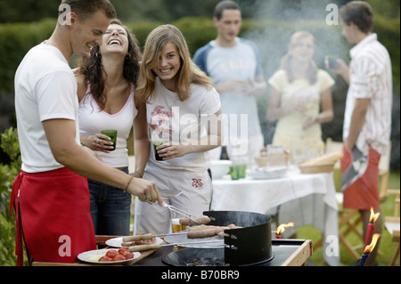 Un gruppo di giovani su un giardino con barbecue Foto Stock