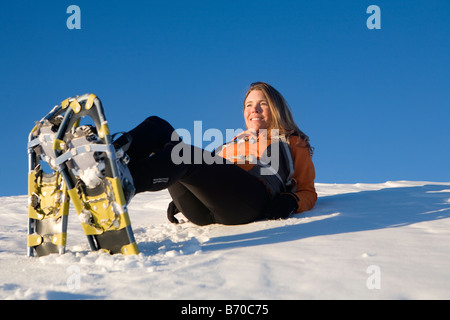 Donna sdraiata sulla neve con le racchette da neve. Foto Stock
